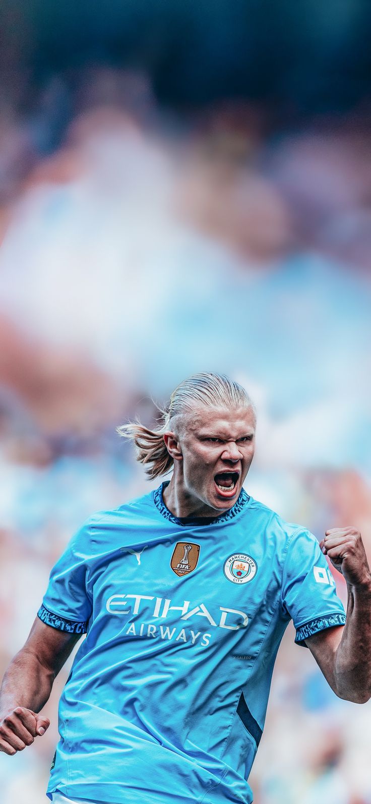 a soccer player with his mouth wide open in front of an audience, wearing a blue uniform