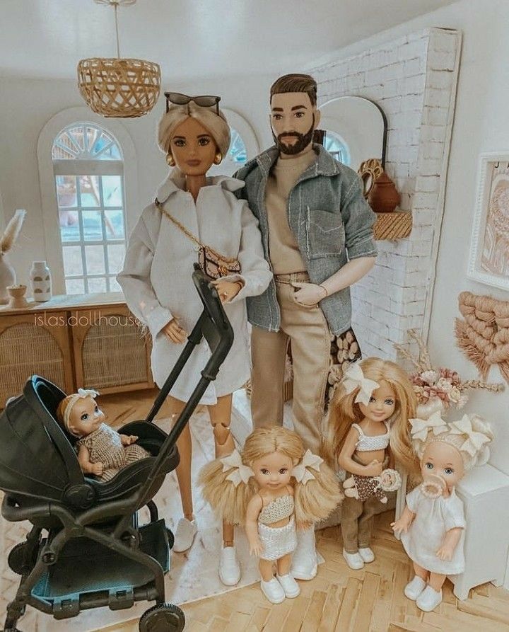 a group of dolls standing next to each other in front of a baby stroller