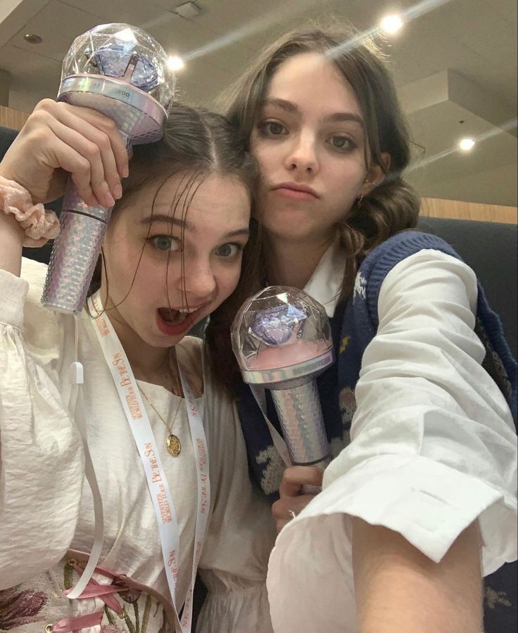 two girls are posing for the camera with their hair dryers in front of them