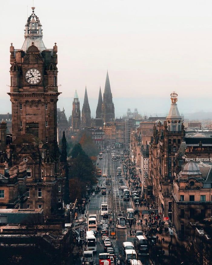 an aerial view of a city street with tall buildings and a clock tower in the distance