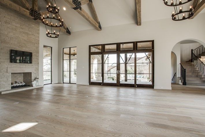 an empty living room with wood floors and chandeliers