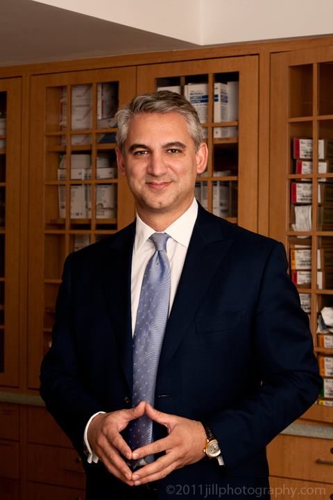 a man in a suit and tie standing in front of a bookcase holding an award