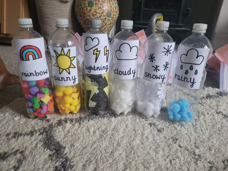 four water bottles with writing on them sitting on the floor next to toys and other items