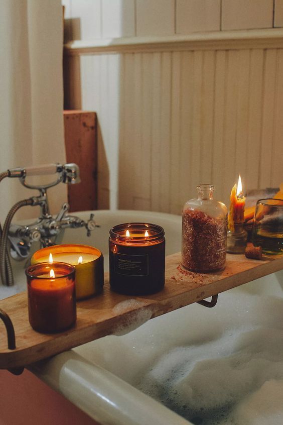 candles are sitting on a wooden tray in the bathtub