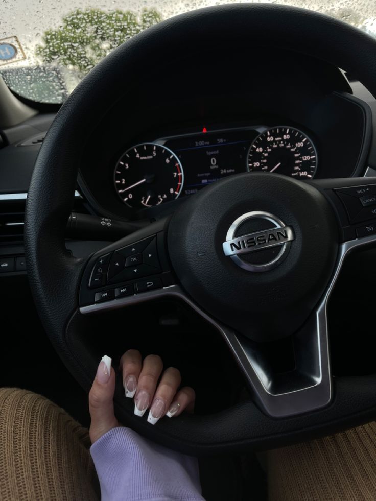 a woman driving a car with her hands on the steering wheel