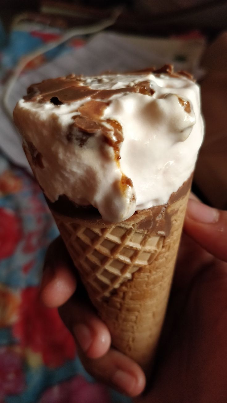 a person holding an ice cream cone in their hand