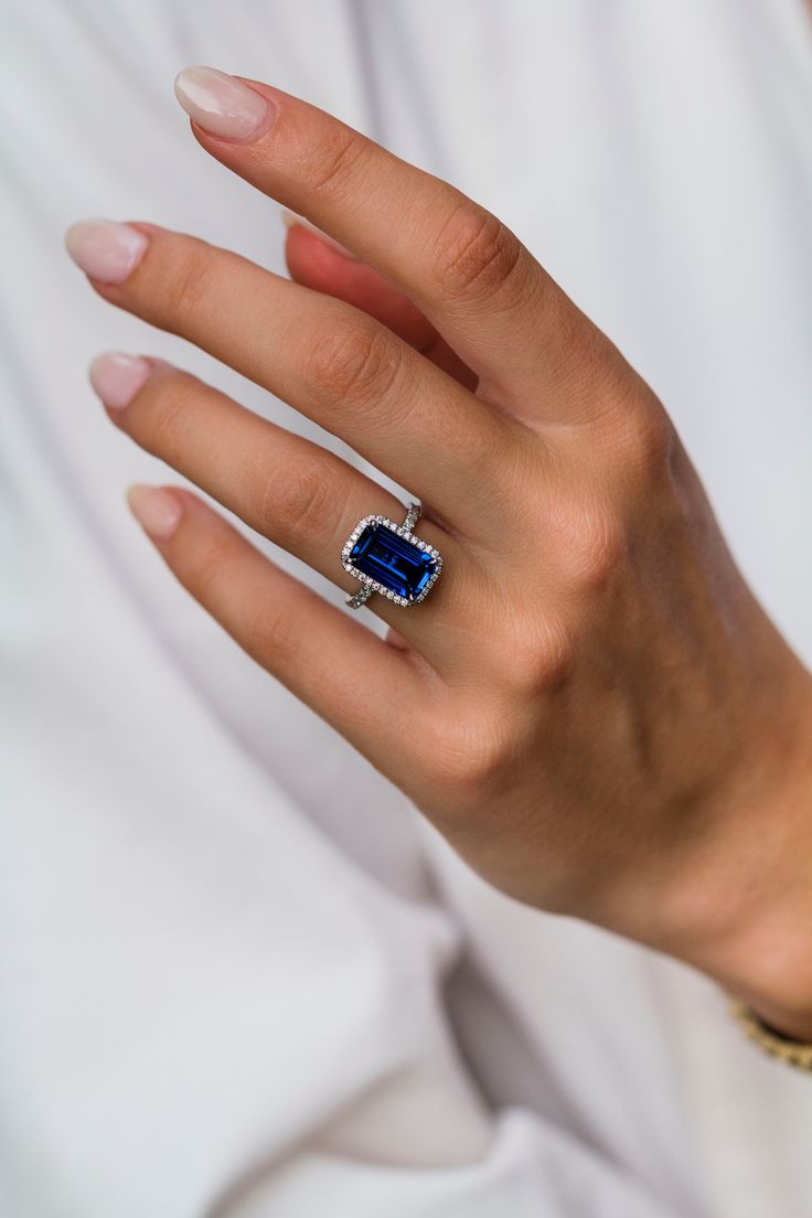 a woman's hand with a ring on it and a blue stone in the middle