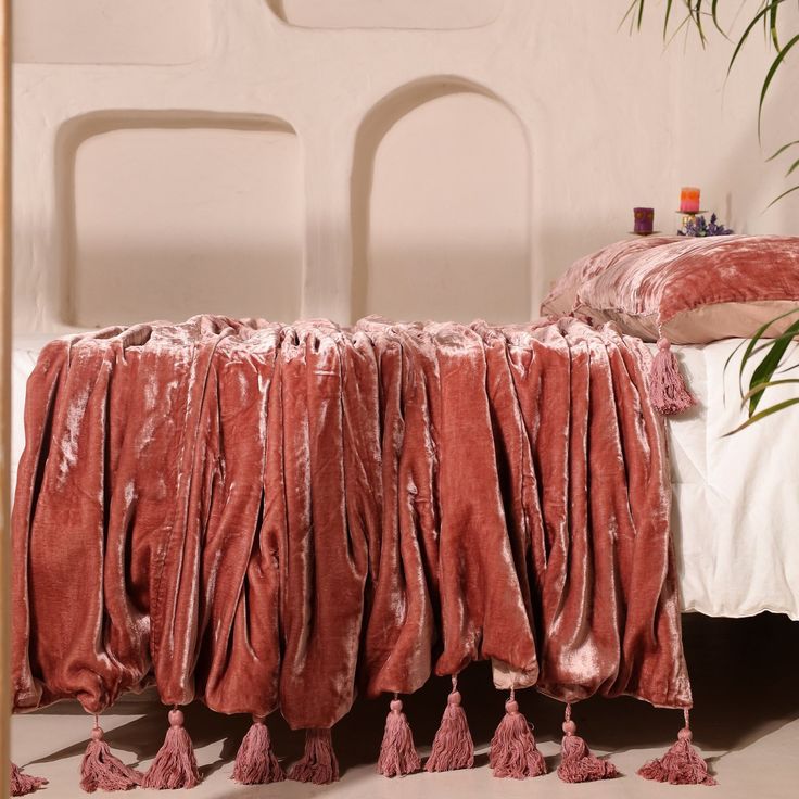 a bed covered in pink velvet with tassels