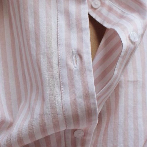 a close up view of a pink and white striped shirt with buttons on the collar