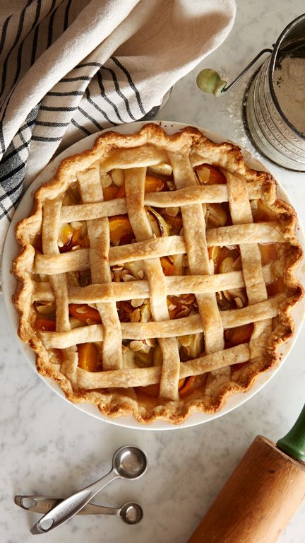 a pie sitting on top of a white plate next to a knife and spoons