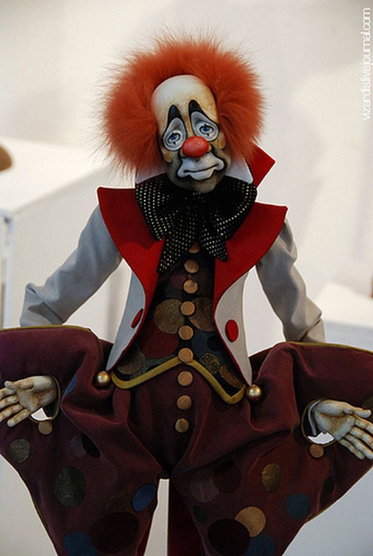 a creepy clown with red hair is posed