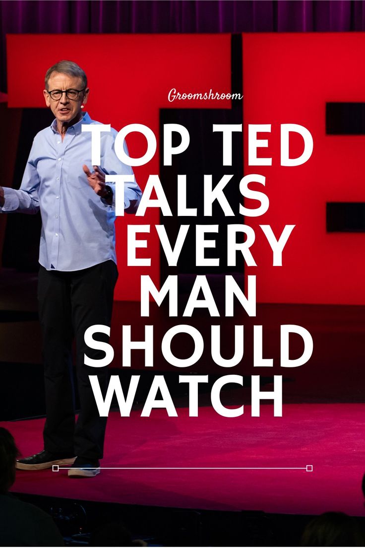 a man standing on top of a stage in front of a red wall with words above it