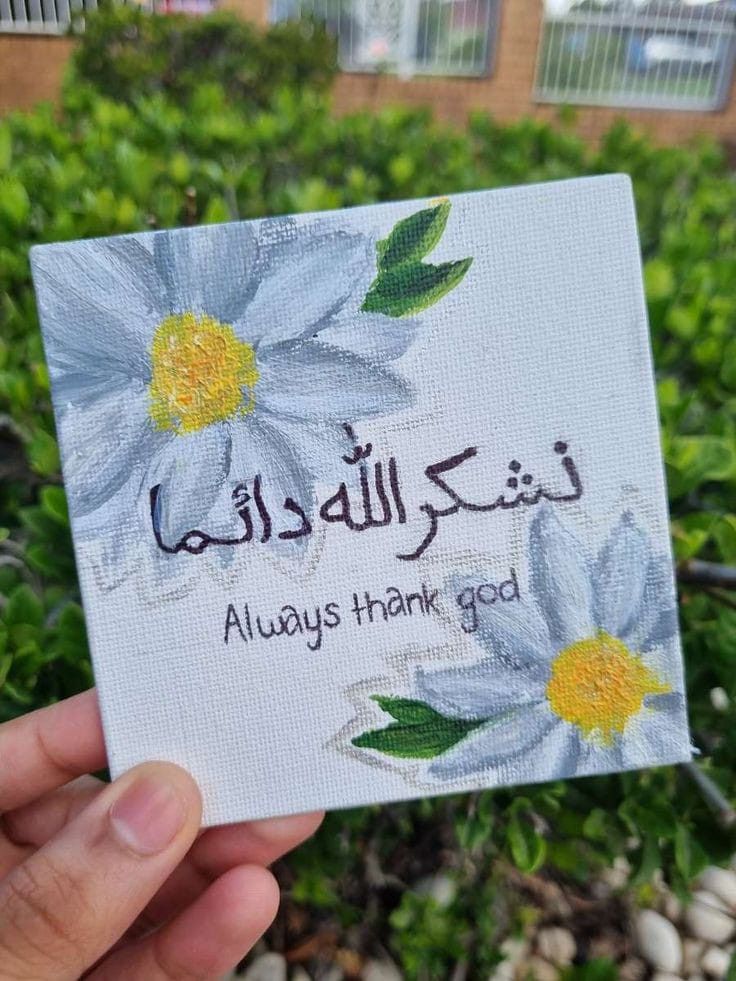 someone holding up a card that says, always thank god in arabic and has flowers painted on it