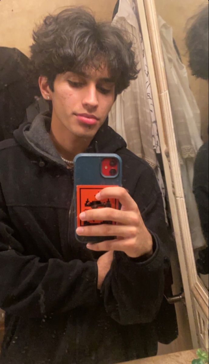 a young man taking a selfie in front of a mirror with his cell phone