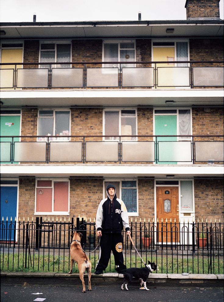 a man walking two dogs in front of an apartment building