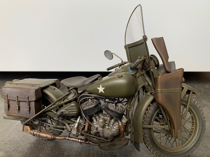 an army green motorcycle is parked on the floor with its luggage strapped to it's back