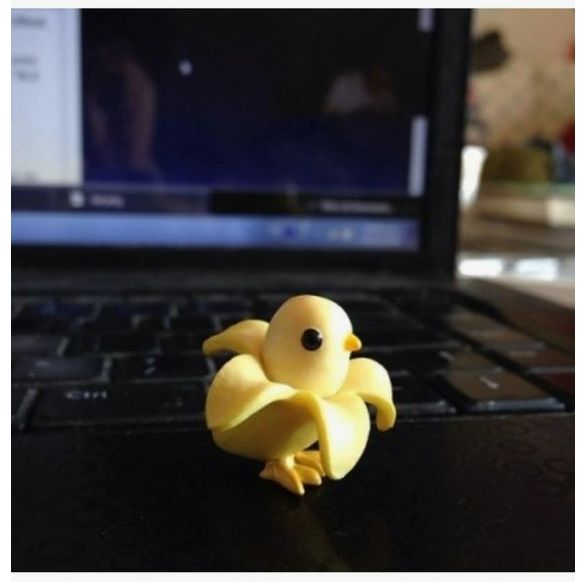 a yellow toy sitting on top of a laptop computer