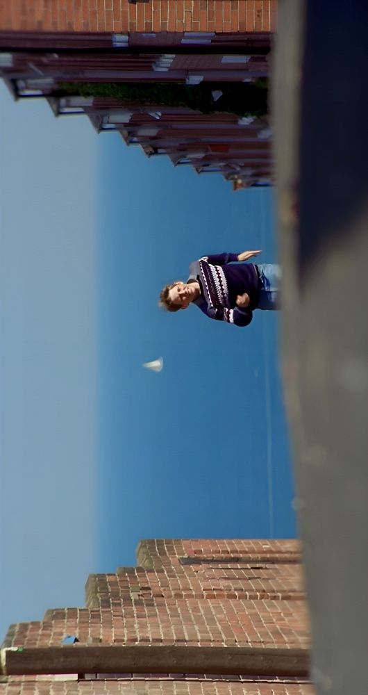 a man flying through the air on top of a brick roof next to a tall building