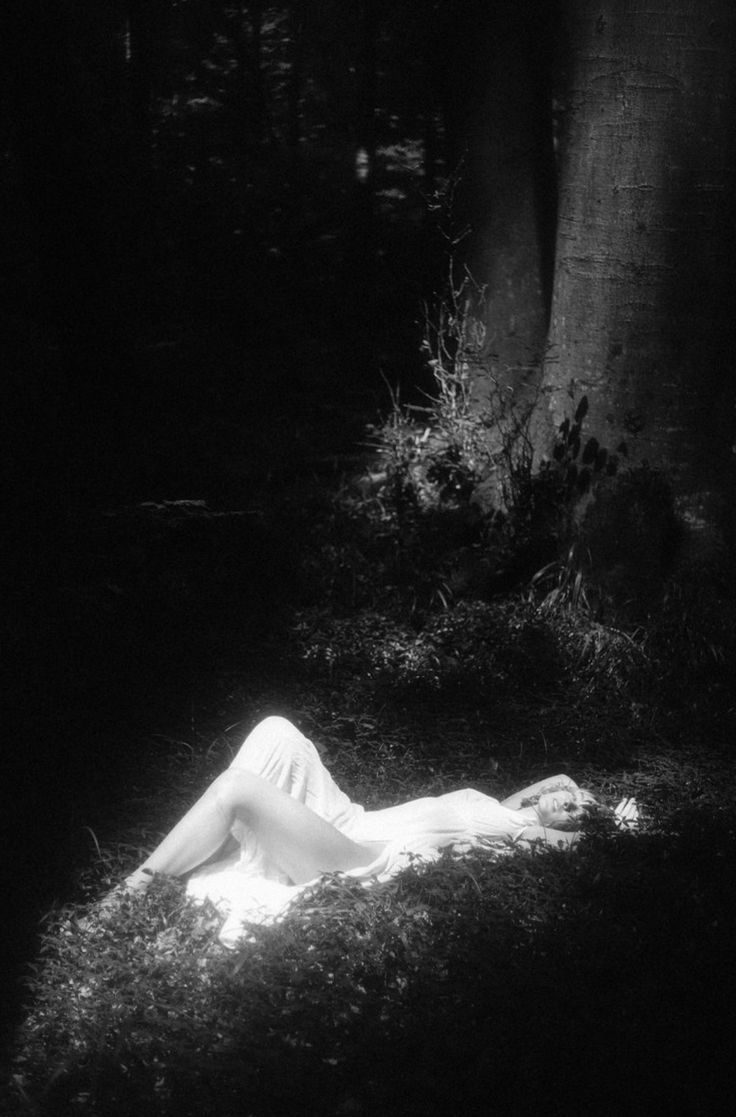 a woman laying on the ground next to a tree