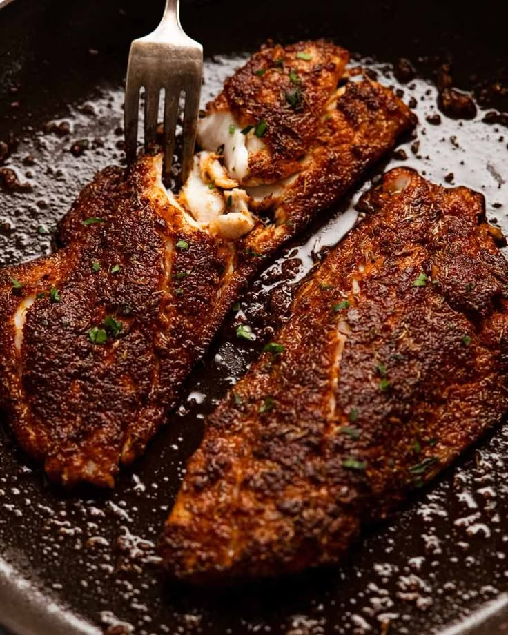 two pieces of meat in a skillet with a fork sticking out of the top