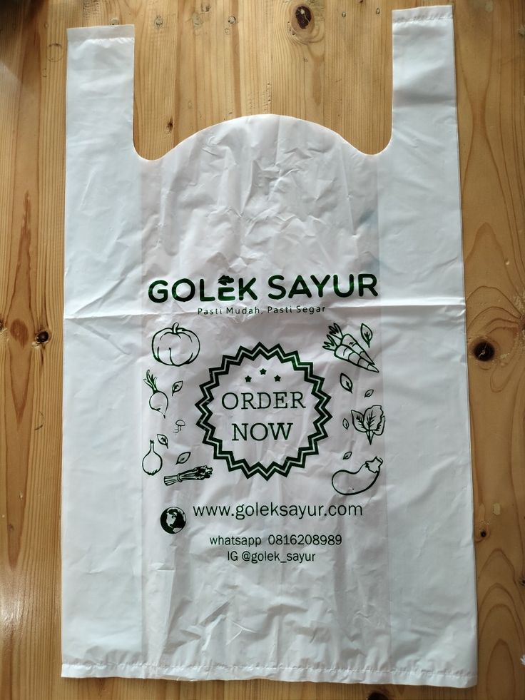 a white paper bag sitting on top of a wooden floor with the words golok sayur printed on it