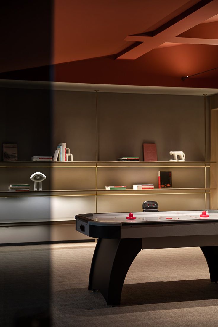 a ping pong table in the middle of a room with shelving behind it