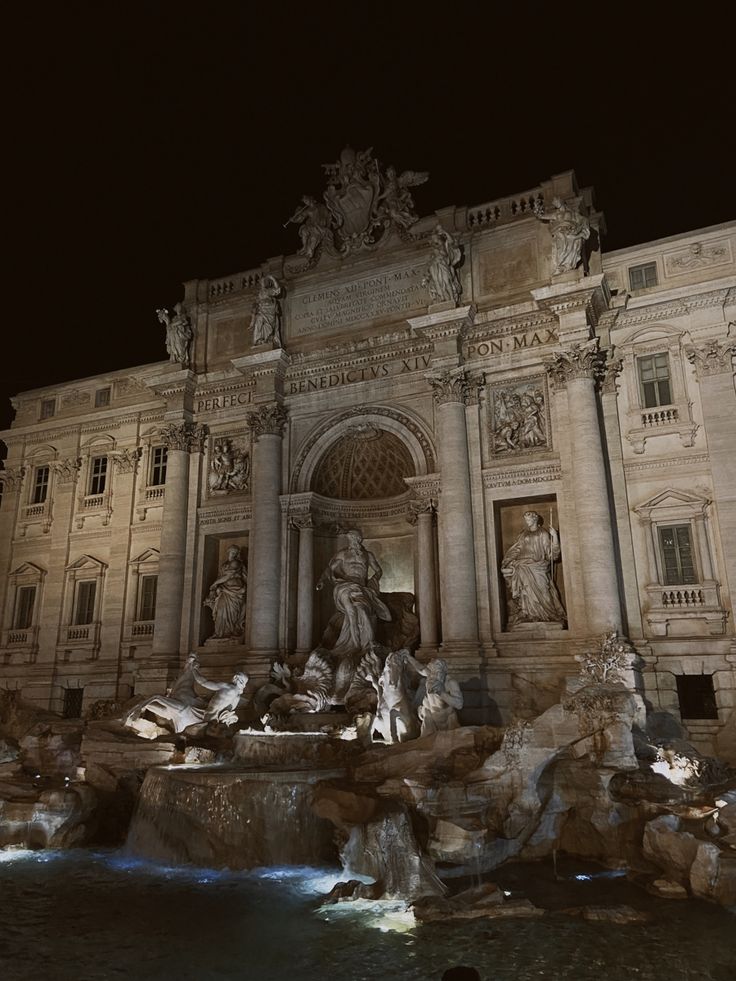 a large building with statues on it at night