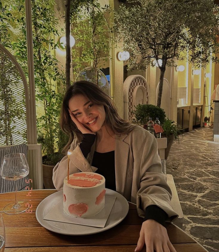 a woman sitting at a table with a cake in front of her