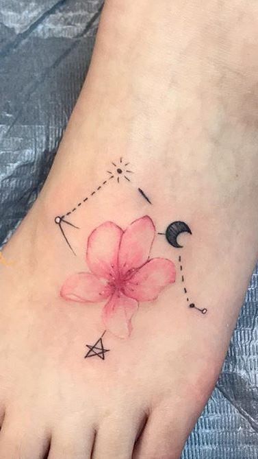 a small flower tattoo on the foot with an arrow and moon in it's center