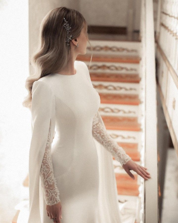 a woman in a white dress is walking down the stairs with her hand on her hip