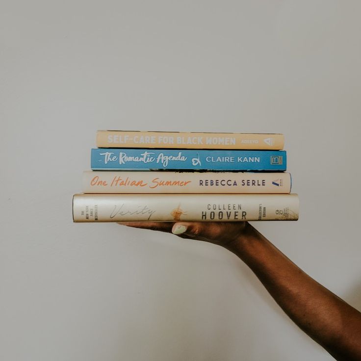 a person holding three books in their hand