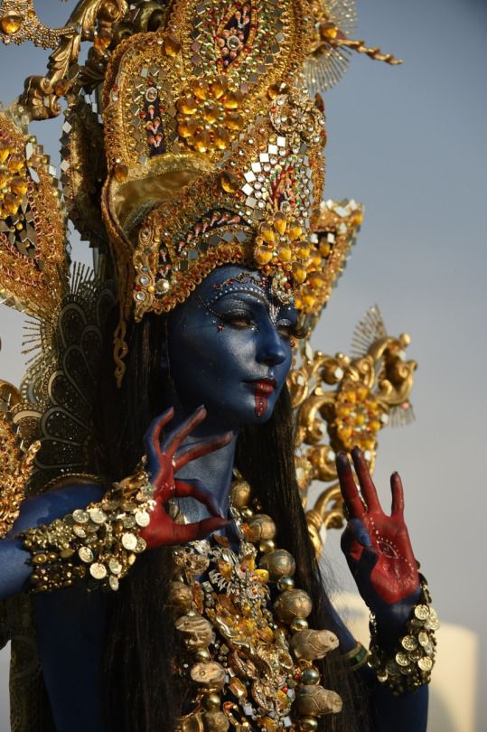 a woman dressed in blue and gold holding her hands up