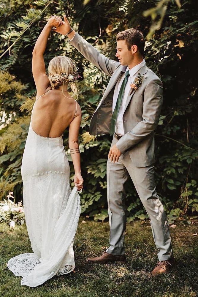 the bride and groom are dancing together in the yard at their outdoor wedding venue, surrounded by greenery