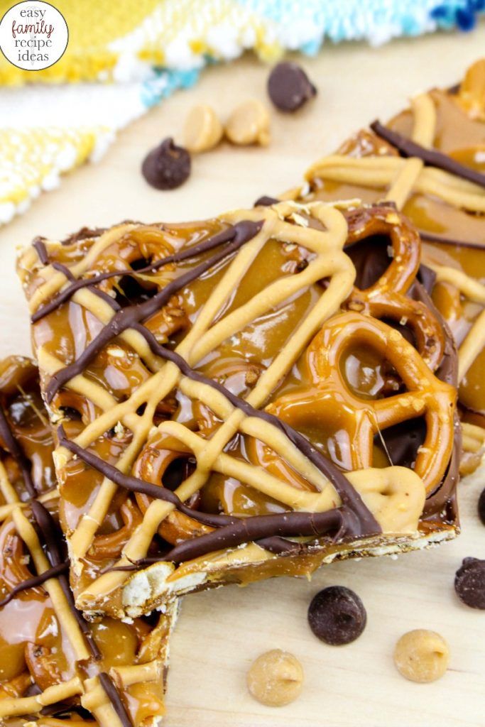 two pieces of chocolate caramel pretzel barkle on a wooden surface with peanuts