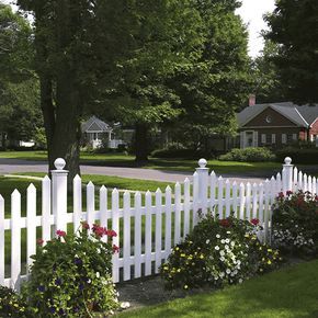 a white picket fence surrounded by flowers and trees