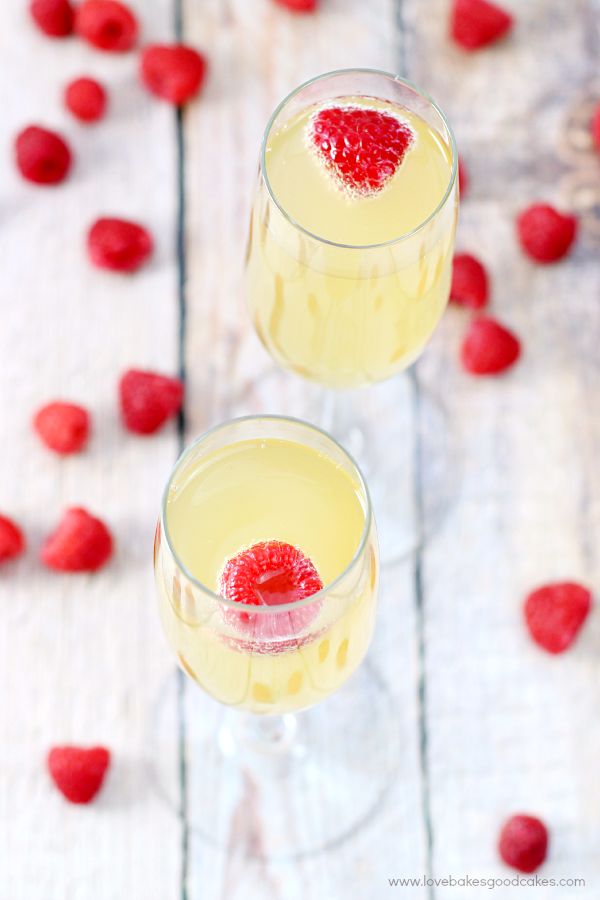 two glasses filled with raspberry lemonade on top of a white wooden table