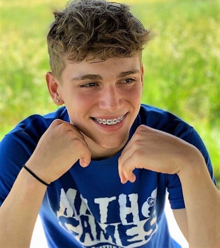 a young boy with braces on his teeth smiles at the camera while posing for a photo