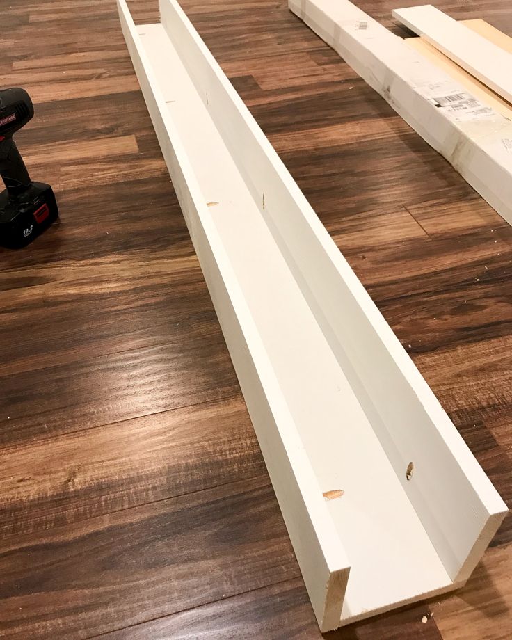 two pieces of wood sitting on top of a hard wood floor next to a power drill