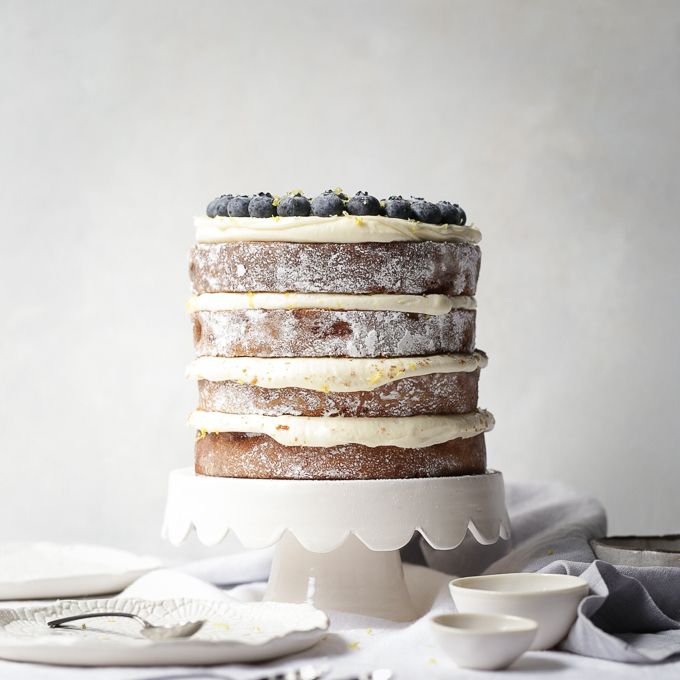 a layered cake with blueberries and cream frosting