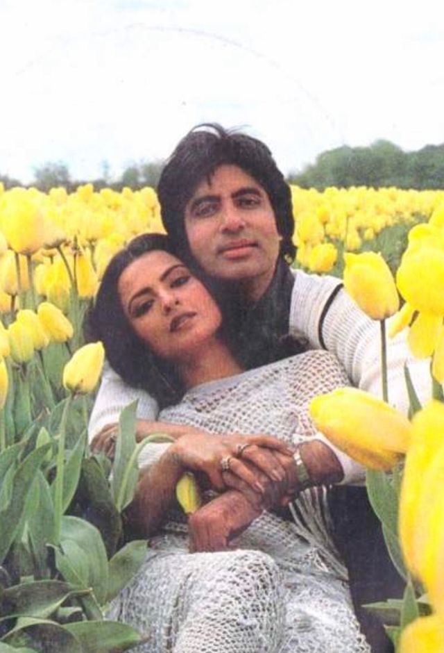 a man and woman sitting in a field of yellow tulips