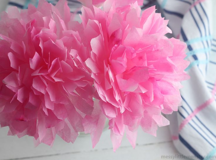 two pink tissue flowers sitting on top of a table