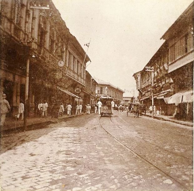 an old black and white photo of people walking down the street in front of buildings