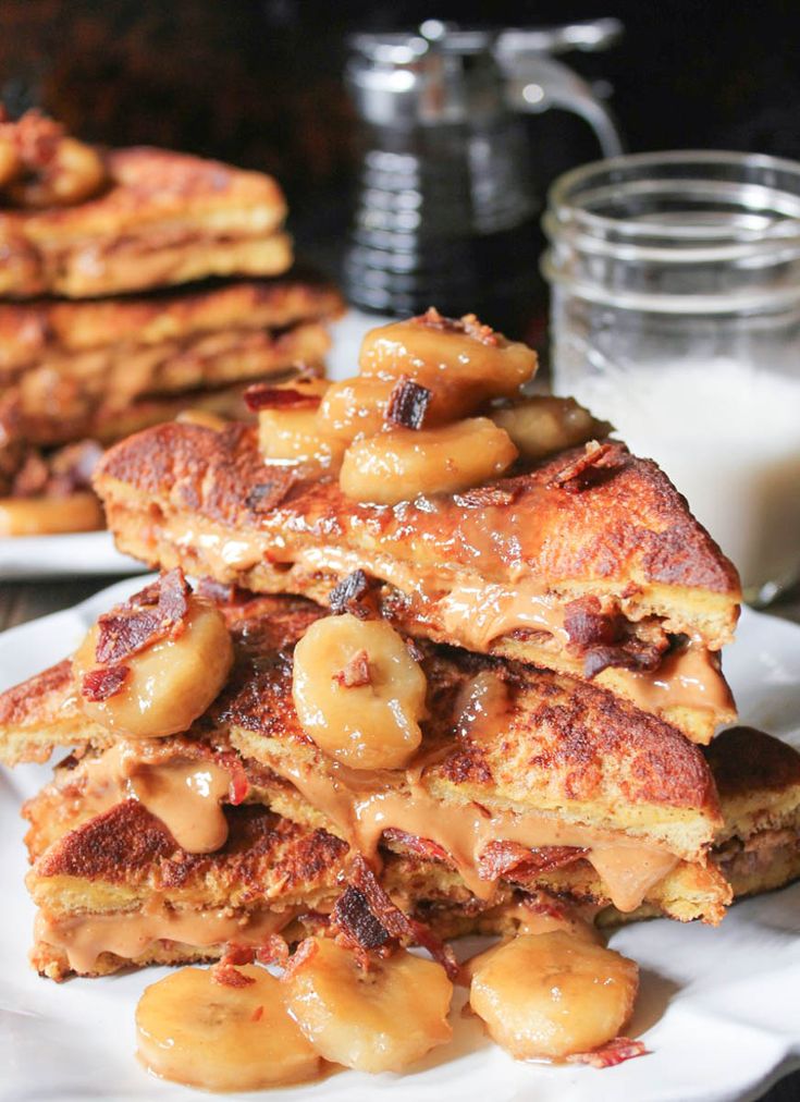 stack of pancakes with bananas and peanut butter on white plate next to glass of milk