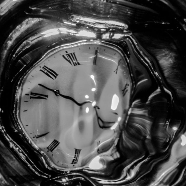 a glass vase with a clock in it's center and water around the edges