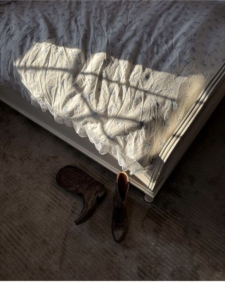 a pair of shoes sitting on top of a bed next to an unmade bed