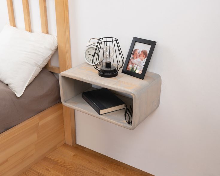 a small shelf on the wall next to a bed with a framed photo and books