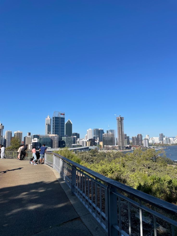 people standing on a bridge looking at the city