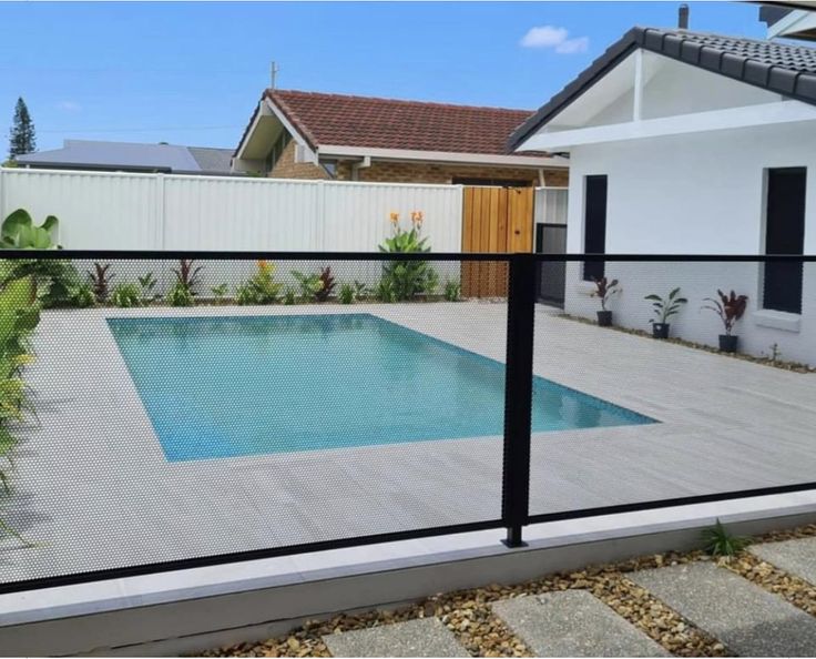 an empty pool in front of a house with a fenced in area around it