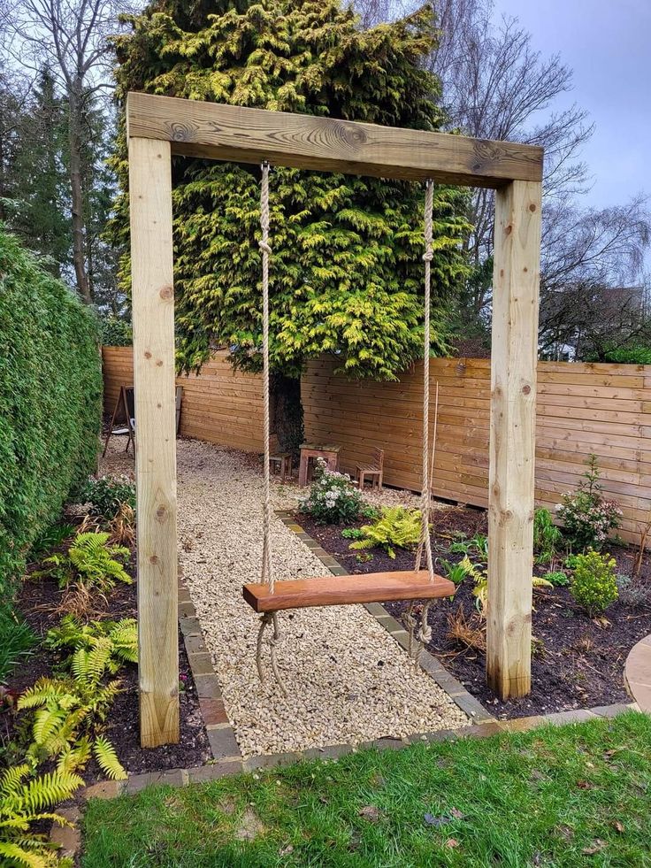 a wooden swing in the middle of a garden