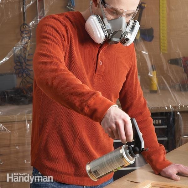 a man in an orange shirt sanding wood with a pair of headphones on